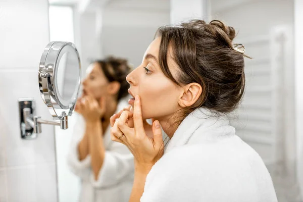 Mujer mirando en su piel en el baño — Foto de Stock