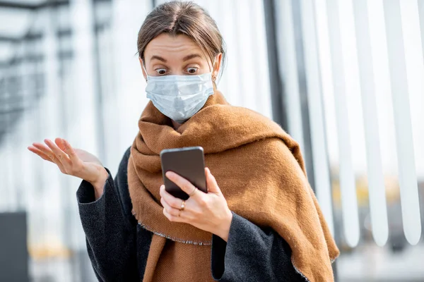 Жінка з маскою обличчя і смартфоном під час епідемії на відкритому повітрі — стокове фото