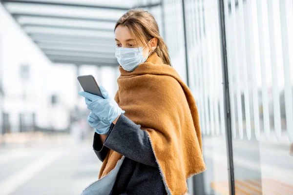 Жінка в масці для обличчя і рукавички зі смартфоном під час епідемії на відкритому повітрі — стокове фото