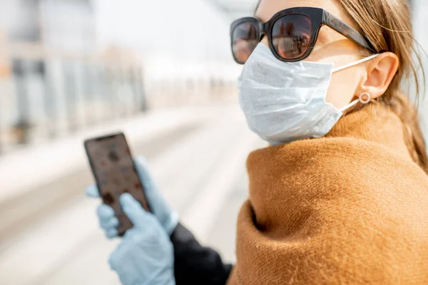 Жінка в медичних рукавичках, використовуючи смартфон на відкритому повітрі — стокове фото