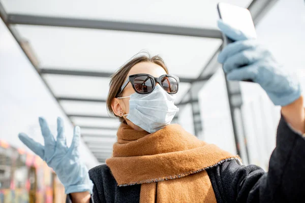 Жінка в масці для обличчя і рукавички зі смартфоном під час епідемії на відкритому повітрі — стокове фото