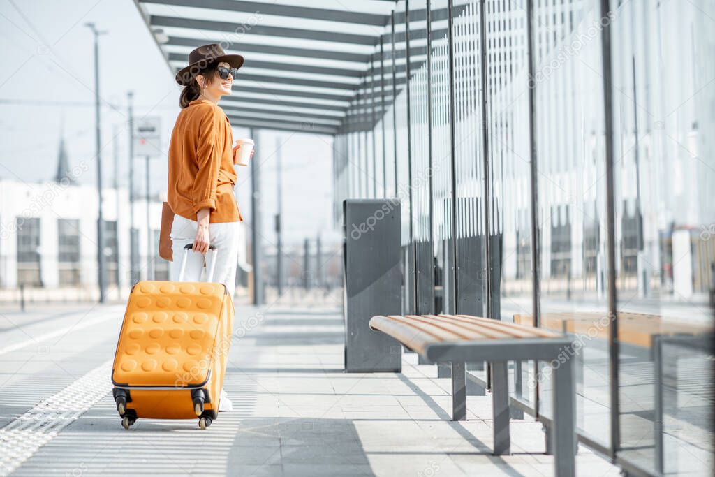 Young female traveler with a luggage at the transport stop
