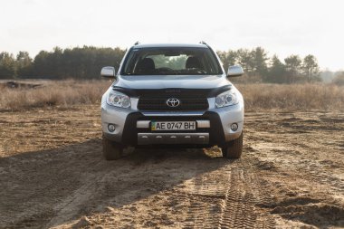 DNIPRO, UKRAINE - FEBRUARY 19, 2020: TOYOTA RAV4 2006 GRAY COLOR AMONG THE SAND NEAR THE FOREST, OPEN SPACE ON SUNSET