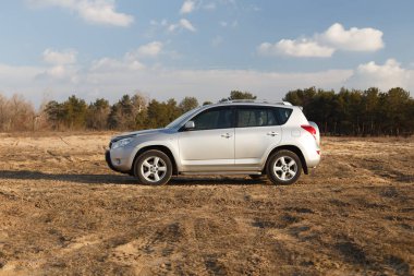 DNIPRO, UKRAINE - FEBRUARY 19, 2020: TOYOTA RAV4 2006 GRAY COLOR AMONG THE SAND NEAR THE FOREST, OPEN SPACE ON SUNSET