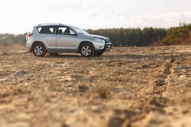 DNIPRO, UKRAINE - FEBRUARY 19, 2020: TOYOTA RAV4 2006 GRAY COLOR AMONG THE SAND NEAR THE FOREST, OPEN SPACE ON SUNSET