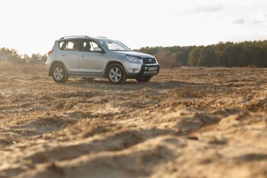 DNIPRO, UKRAINE - FEBRUARY 19, 2020: TOYOTA RAV4 2006 GRAY COLOR AMONG THE SAND NEAR THE FOREST, OPEN SPACE ON SUNSET