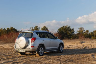 DNIPRO, UKRAINE - FEBRUARY 19, 2020: TOYOTA RAV4 2006 GRAY COLOR AMONG THE SAND NEAR THE FOREST, OPEN SPACE ON SUNSET