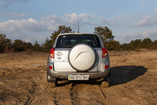 DNIPRO, UKRAINE - FEBRUARY 19, 2020: TOYOTA RAV4 2006 GRAY COLOR AMONG THE SAND NEAR THE FOREST, OPEN SPACE ON SUNSET