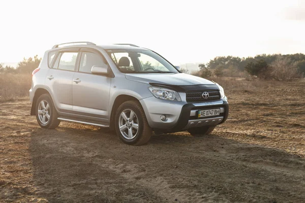DNIPRO, UKRAINE - FEBRUARY 19, 2020: TOYOTA RAV4 2006 GRAY COLOR AMONG THE SAND NEAR THE FOREST, OPEN SPACE ON SUNSET