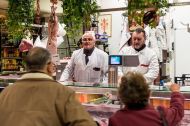 FLORENCE, ITALY - 25, MARCH, 2016: Italian vendors selling meat inside Mercato Centrale Firenze, a touristic destionation of Florence, Italy clipart