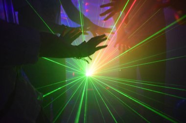 Parlak disko ışınlarıyla dans eden insanların elleri.