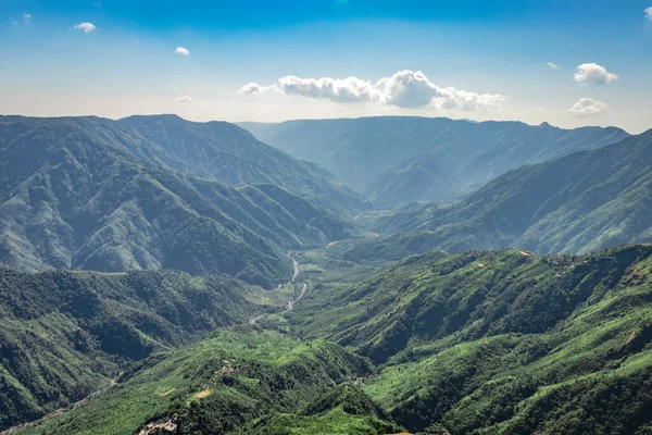 misty mountain range covered with white mist and amazing blue sky image showing the beautiful natural landscape of hill range. Image is taken at latilum peak shillong meghalaya india.