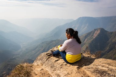 Bu güzel dağ sırasını dağ görüntüsünün kenarından izleyen kız, Hindistan 'daki Laytilum Peak Shillong Meghalaya Tepesi' nden alınmıştır. Burası ayrıca Şillong 'un Büyük Kanyonu olarak da bilinir..