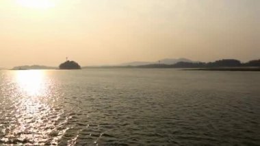 Nehir adası gün batımında, arka planda dağ klibiyle