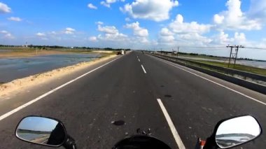 Asfalt klip yolunda motosiklet sürücüsü inanılmaz mavi gökyüzü ve bulut yaması klipsi ile seyahat etmenin güzelliğini gösteren motosiklet sürüşü çekilirken.