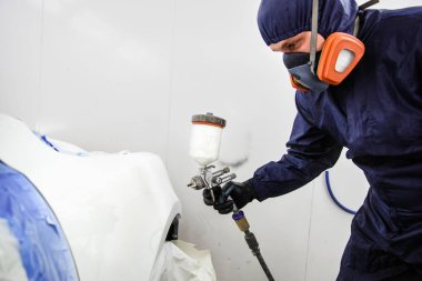 Sprey kabininde sprey tabancası olan işçi