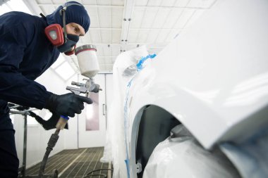 Sprey kabininde sprey tabancası olan işçi