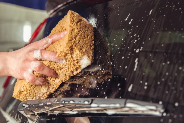 Puerta de coche de cristal con espuma y una mano con una esponja de espuma — Foto de Stock