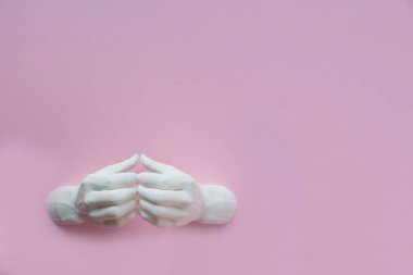 Pembe arka planda birbirine bağlı 3D plastikten iki el heykel. Minimalizm, metin yeri, üst görünüm