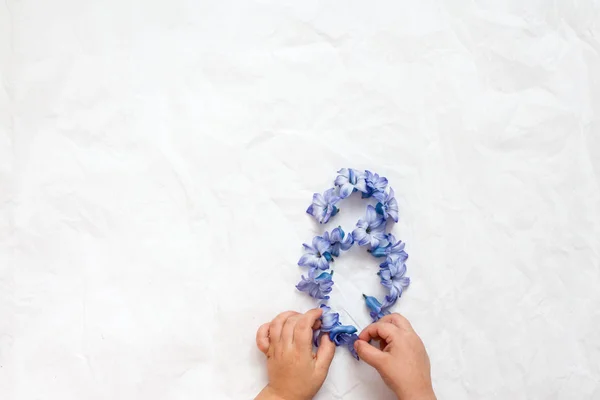 the childrens hands make eight of the flowers of blue hyacinth flowers for mom on International Womens Day. greeting card, place for an inscription