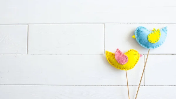 Весняний домашній декор. Великодня концепція. Жовті та сині птахи ручної роботи на палицях на білому тлі . Ліцензійні Стокові Фото