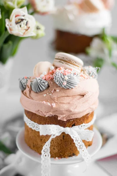 Påskkaka kulich.Traditionellt påsk sött bröd dekorerat med maränger och makaroner på en tallrik på en bakgrund av en vas med vita tulpaner. Kopiera utrymme — Stockfoto