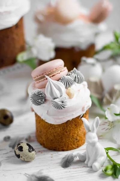 Tort de Paști kulich.Pâine dulce tradițională de Paști decorată cu meringi și macaroane pe o farfurie pe fundalul unei vase cu lalele albe. Copiați spațiul — Fotografie, imagine de stoc