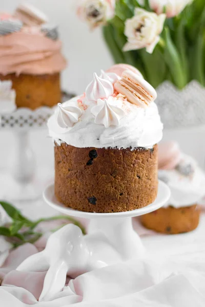 Torta pasquale kulich.Traditional pasqua dolce pane decorato con meringhe e amaretti su un piatto su uno sfondo di un vaso con tulipani bianchi. Copia spazio — Foto Stock