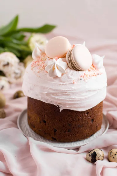 Påskkaka kulich.Traditionellt påsk sött bröd dekorerat med maränger och makaroner på en tallrik på en bakgrund av en vas med vita tulpaner. Kopiera utrymme — Stockfoto