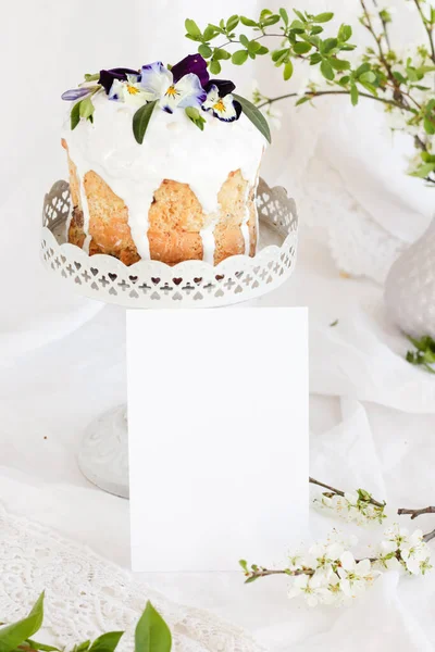 Panetton tradizionale pasquale con decorazione floreale e glassa bianca su fondo bianco con uova bianche fantasia e biglietto di auguri per un'iscrizione . — Foto Stock