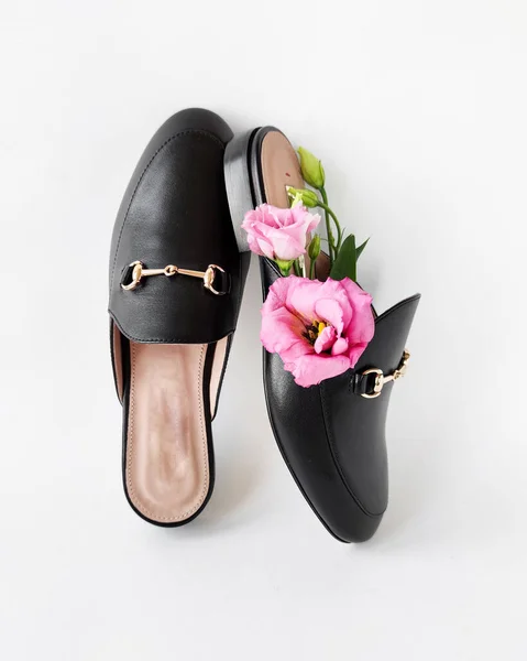 Zapatos femeninos de moda de la mula negra con flores rosadas del eustoma sobre un fondo blanco . —  Fotos de Stock