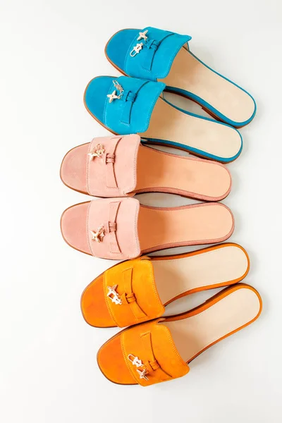 Elegantes zapatos de primavera o verano para mujer, chanclas de diferentes colores sobre un fondo blanco. amarillo, rosa, palomas para pasear por la playa. Piso tendido, vista superior —  Fotos de Stock