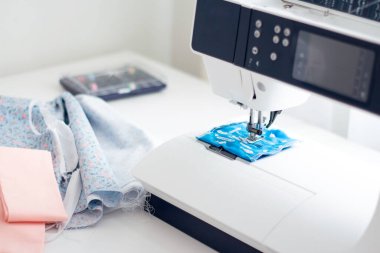 Kadın elleri dikiş makinesinin yanında bir parça doğal pamuk tutuyor..