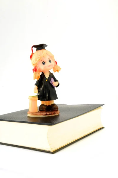 Graduation doll on the book. — Stock Photo, Image