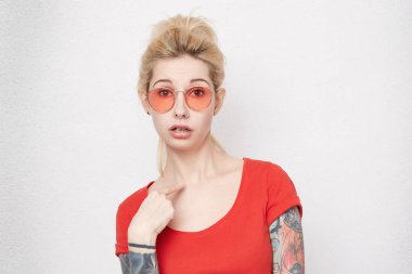Beni? Güzel kız portresi kırmızı t-shirt noktası parmak kendisi ile giyer ve korkmuş ve şok hissediyor. Beyaz beton duvardan izole