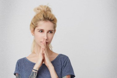 Ne yaptık? Astanished ve bir yana, seyir üzgün genç güzel sarışın kız portre dua ediyor ve geleceğini düşün. Beyaz duvardan izole