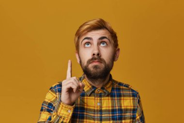 Yakışıklı Kızıl sakallı erkek noktası parmak yukarıda ve orada ciddi seyir ile boyalı. Sarı arka plan üzerinde izole