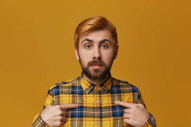 Genç redhead damalı sarı tişört şaşkın ve onun kendini bir parmağında noktasıyla hayran erkek giyer sakallı. Sarı arka plan üzerinde izole