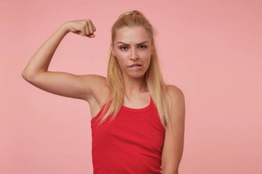 Çekici bir genç bayanın, kameraya tehditkar bir şekilde baktığı pohpohlanmış elini gösteren, kaşlarıyla oynayan ve dudağını ısıran bir fotoğraf.