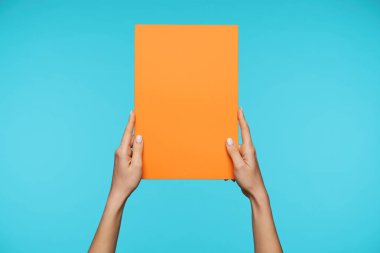 Seçkin bir bayanın, mavi arka planda dikdörtgen şeklinde duran turuncu kağıdını tutarken çekilmiş bir fotoğraf. Gayri resmi kadınlar duygularını paylaşır