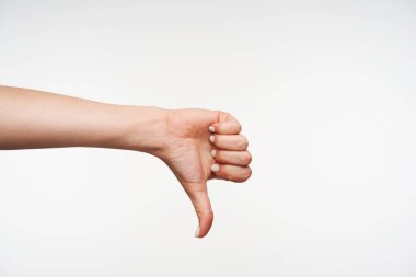 Stüdyo fotoğrafında, beyaz arka planda izole edilmiş, negatif duyguları dışa vururken, genç ve çekici bir kadının eli baş parmağıyla görülüyor.