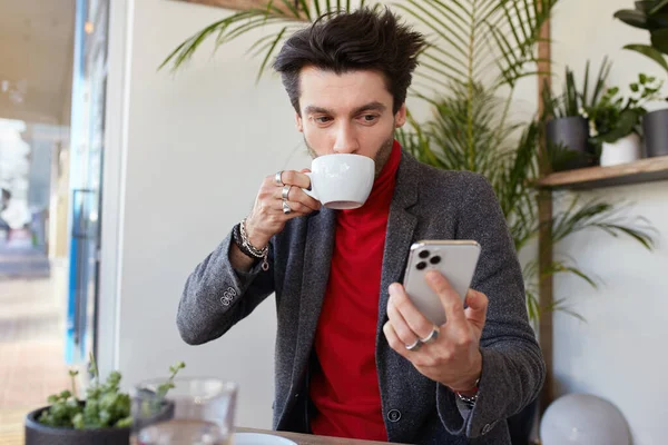 카페에서 커피를 마시면서우아 머리의 남자가 스마트폰을 스크린에서 긍정적으로 보이는 내장되어 — 스톡 사진