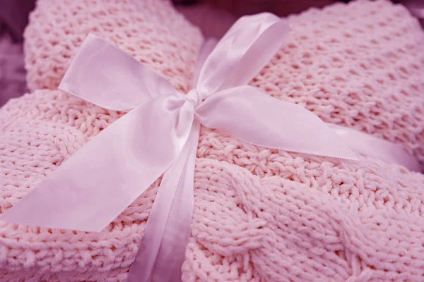 A soft knitted blanket is folded and tied with a white ribbon with a bow. The concept of comfort and coziness. Gift for the holiday.