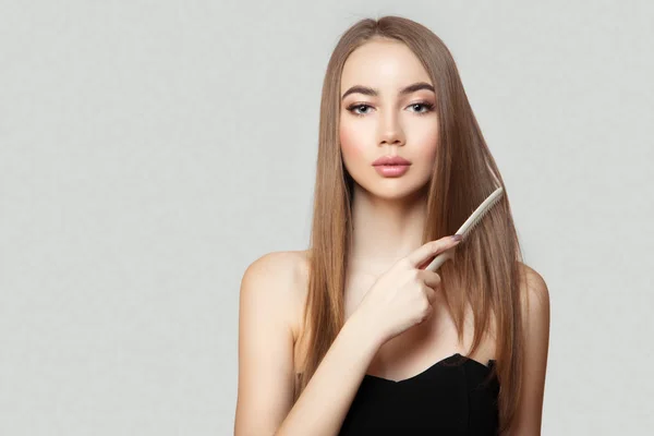 Güzel genç bir kadın parlak düz saçlarını tarıyor. Bir portre üzerinde