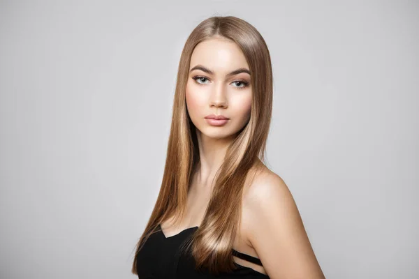 Parlak saçlı ve makyajlı güzel bir kadın. Gri arka planda bir portre. Temiz cilt, kaldırma 