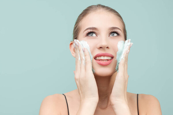 Happy woman is applying a moisturizing mask to her face. blue ba
