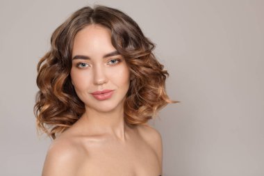 Gülümseyen genç bir kadının portresi. Gönüllü dalgalı saçlar. beyaz arkaplan