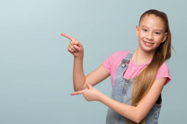 Genç liseli kız boş alanı işaret ediyor. Mutlu bebek portresi