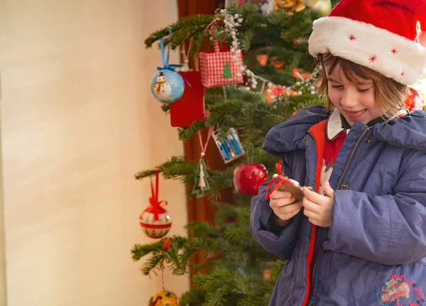 Çocuk Noel ağacının önünde süs eşyalarıyla oynuyor