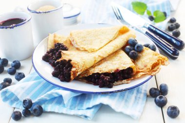 Mavi ve beyaz arkaplanda yaban mersinli krep